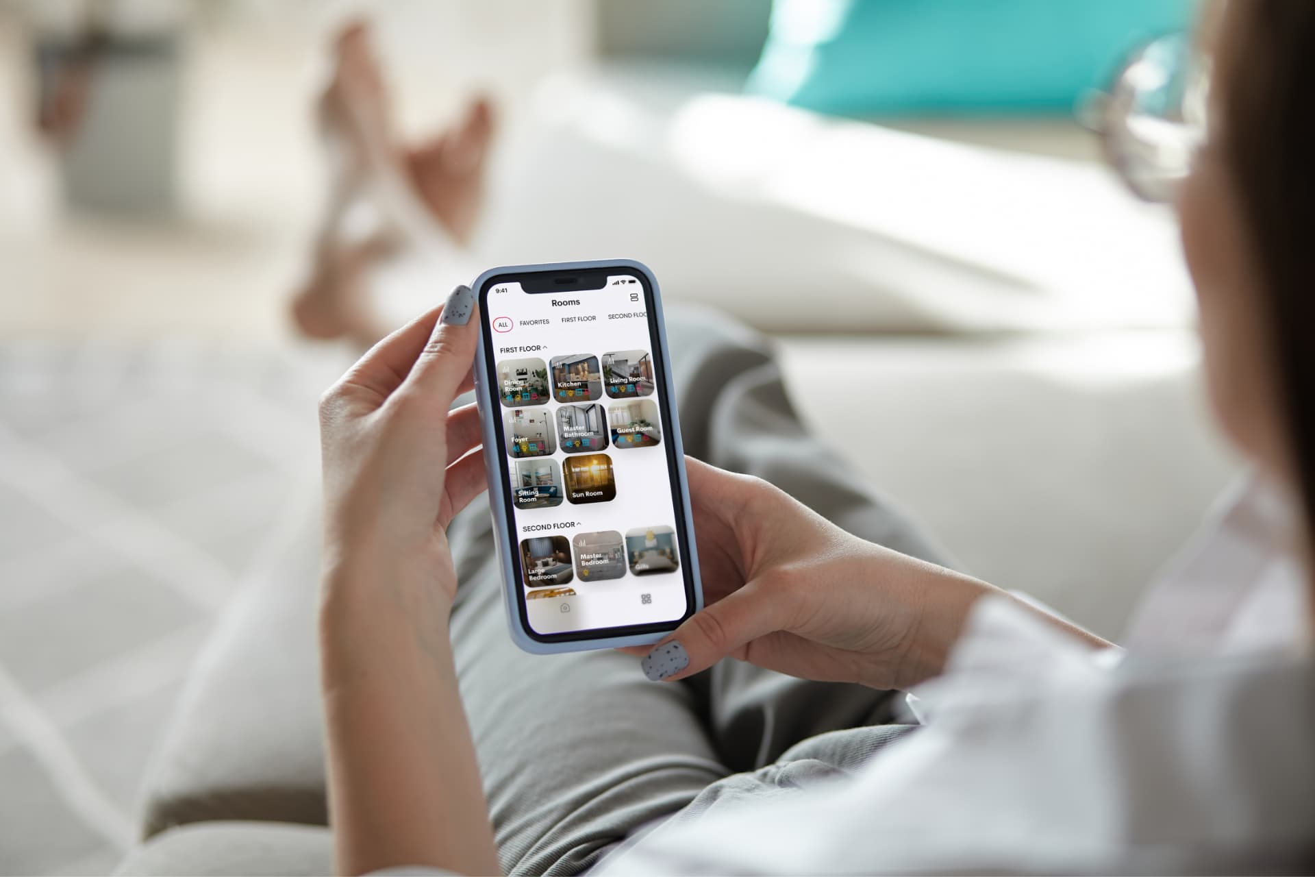 Homeowner using the Crestron Home app on an iPhone to view rooms, scenes and status while away from the residence