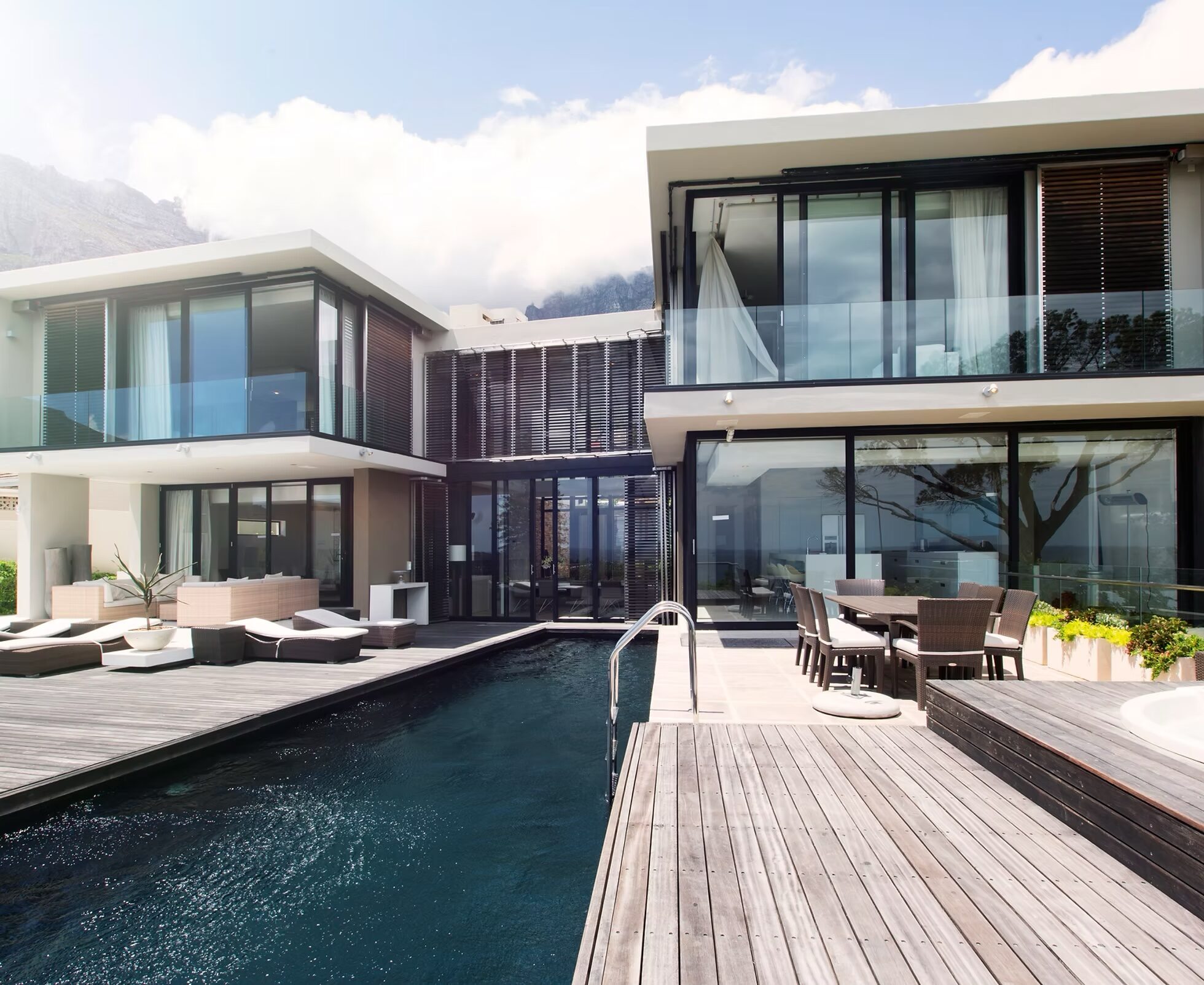 Contemporary two-storey New Zealand residence with full-height glass facades, timber deck and lap pool, fitted with integrated lighting, shading and outdoor audio
